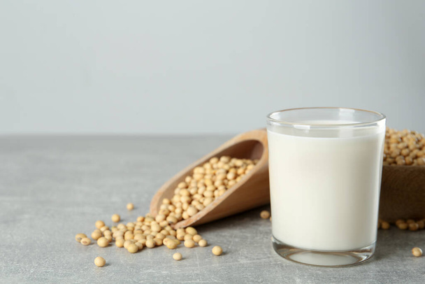 Glass with fresh soy milk and grains on grey table. Space for text - Photo, image