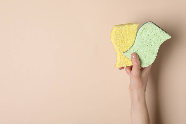 Woman holding sponges on beige background, top view. Space for text - Zdjęcie, obraz