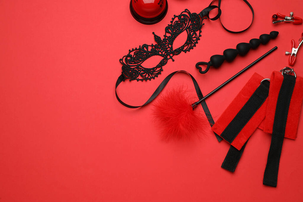 Sex toys and accessories on red background, flat lay. Space for text - 写真・画像