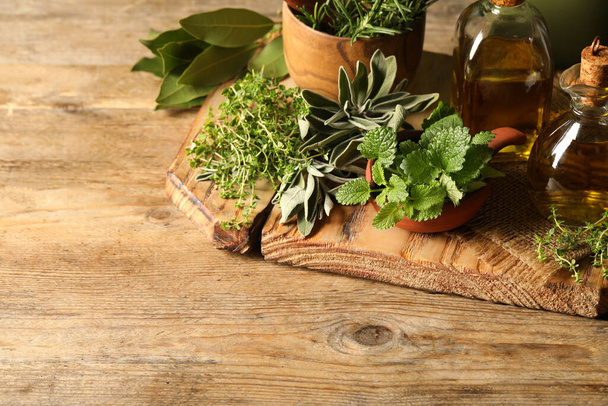 Different fresh herbs with oils on wooden table. Space for text - Foto, Imagen