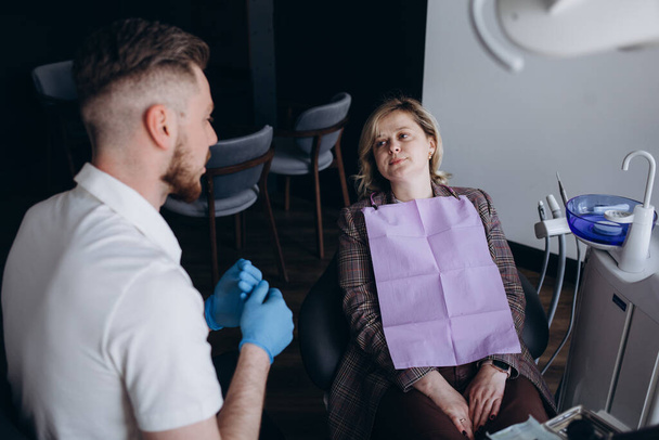 Vaalea nainen istuu hammaslääkärin tuolissa ja käy hammaslääkärin tarkastuksessa. Valikoiva painopiste
 - Valokuva, kuva