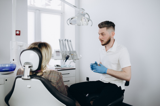 Man tandarts met behulp van digitale tablet en praten met zijn patiënt in de tandheelkundige kliniek. - Foto, afbeelding