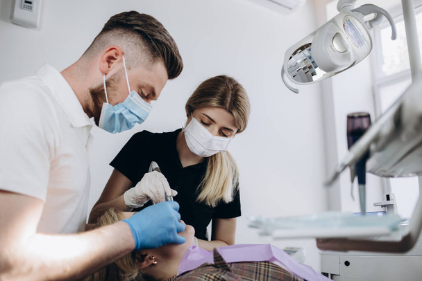 Két fogorvos vizsgálja meg a beteg fogait. Modern fogászati szekrény. Fogászat, orvostudomány, orvosi berendezések és fogászati koncepció - az új modern fogászati klinika belseje. - Fotó, kép