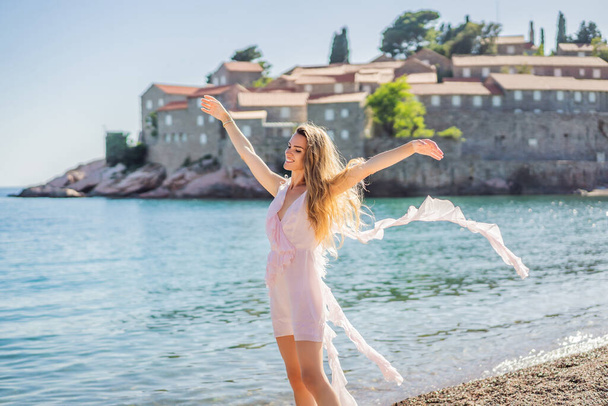 Woman tourist on background of beautiful view of the island of St. Stephen, Sveti Stefan on the Budva Riviera, Budva, Montenegro. Travel to Montenegro concept. - Photo, Image