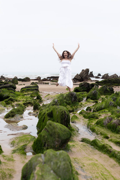 woman in white dress jumping on the beach - Foto, afbeelding