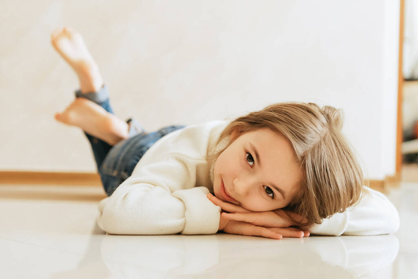 niña 9 años de edad con pelo largo modelo colegiala en el estilo de vida en casa sobre un fondo beige estilo retrato de moda sentado en el suelo - Foto, imagen