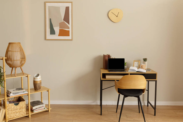 Modernes, helles Home-Office-Interieur mit Schreibtisch und Laptop, Mockup auf PC-Bildschirm. Zeitgenössisches Zimmer in Pastellfarben mit Tisch und tragbarem Computer. Skandinavischer Stil, einfaches Design - Foto, Bild