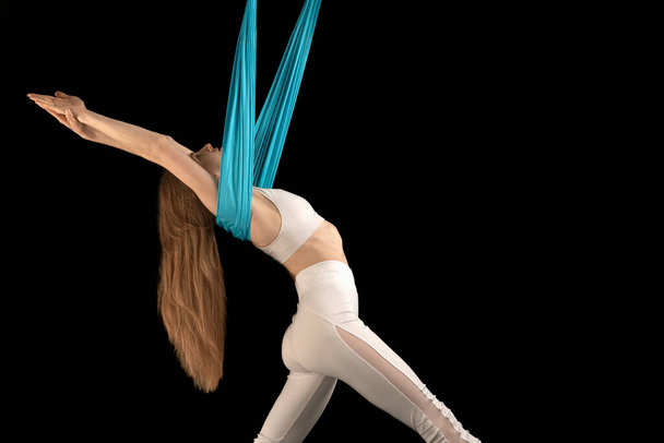 Jovem mulher esporte fazendo exercício de ioga mosca para alongamento em rede. Vista lateral isolada sobre fundo preto - Foto, Imagem
