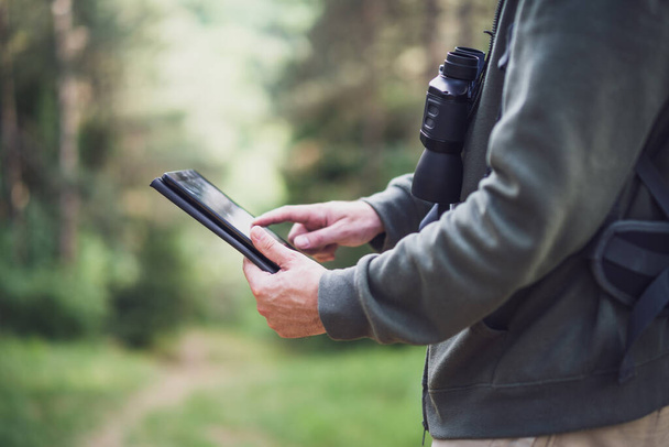 Kép túrázó segítségével digitális tablet, miközben időt tölt a természetben. - Fotó, kép