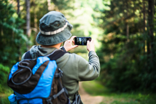 Image of man enjoys hiking and making pictures  with his phone. - Foto, Imagem