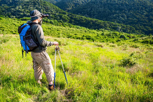 Image of man hiking and using binoculars. - Foto, afbeelding
