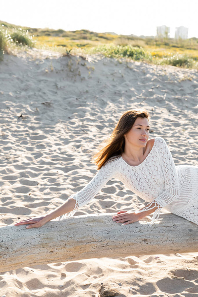 Woman in summer white dress posing on wooden log on beach  - Fotografie, Obrázek