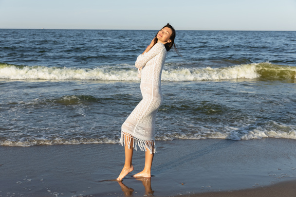 Pretty woman closing eyes while standing in sea water on beach  - Zdjęcie, obraz