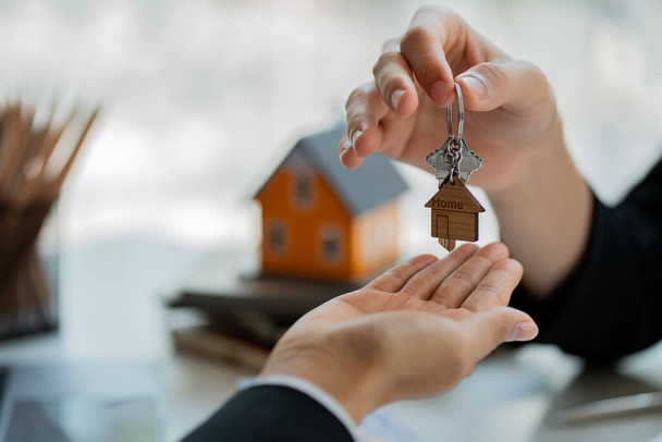 Le vendeur remet les clés de la maison au client, de la vente de la maison, et des échantillons avec le contrat d'achat de la maison au client qui achète la maison. avec assurance immobilière - Photo, image
