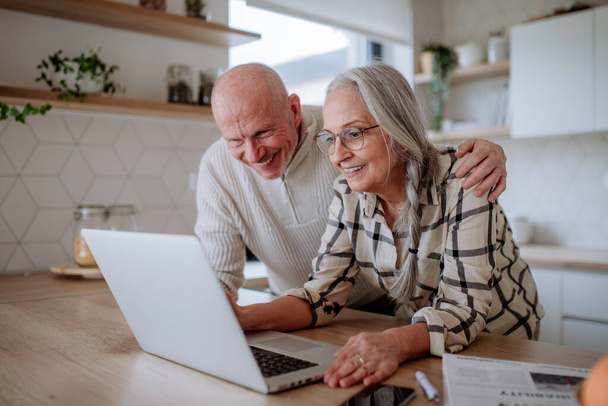 A happy senior couple calculate expenses or planning budget together at home. - Фото, зображення