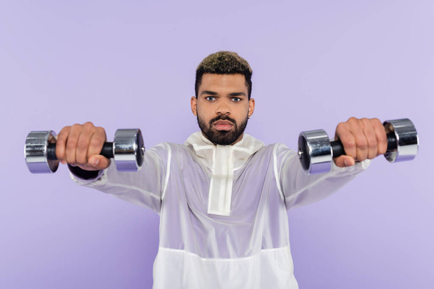 bearded african american man exercising with dumbbells isolated on purple  - Foto, imagen