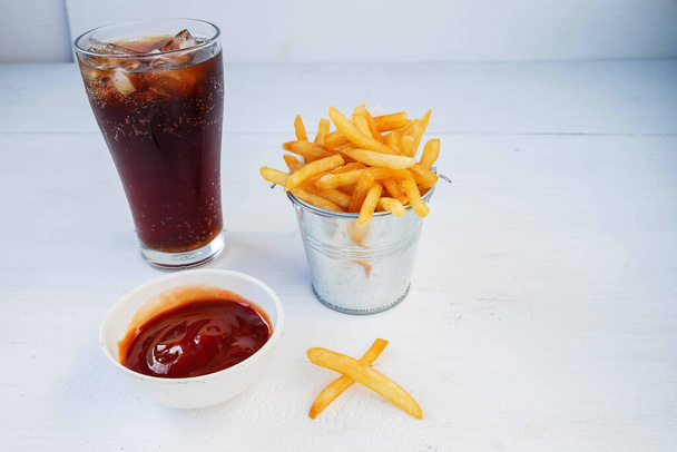 Смажена картопля фрі та кетчуп з безалкогольними напоями на столі
 - Фото, зображення