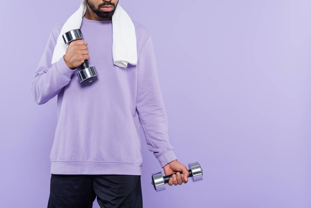 vista recortada del hombre afroamericano barbudo con ejercicio de toalla mientras sostiene pesas aisladas en púrpura  - Foto, imagen