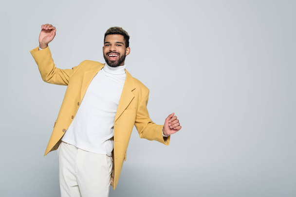 excited african american man in stylish yellow blazer posing isolated on grey  - Foto, Imagem