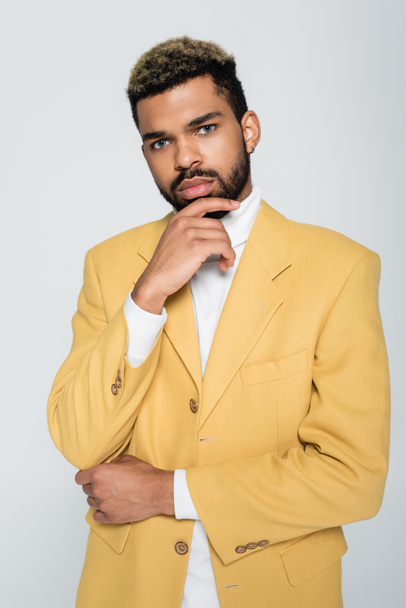young african american man with blue eyes in stylish yellow blazer looking at camera isolated on grey  - Valokuva, kuva