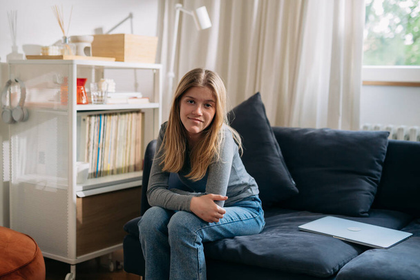 teenager caucasian girl sitting on sofa and looking at camera - Foto, immagini