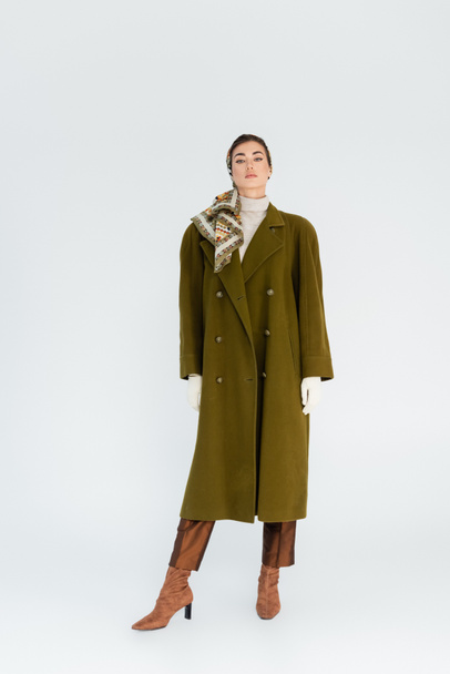 full length of woman in green stylish coat and headscarf looking at camera on white background - Photo, Image