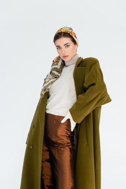 elegant woman in green coat and brown trousers standing with hand on hip isolated on white - Valokuva, kuva