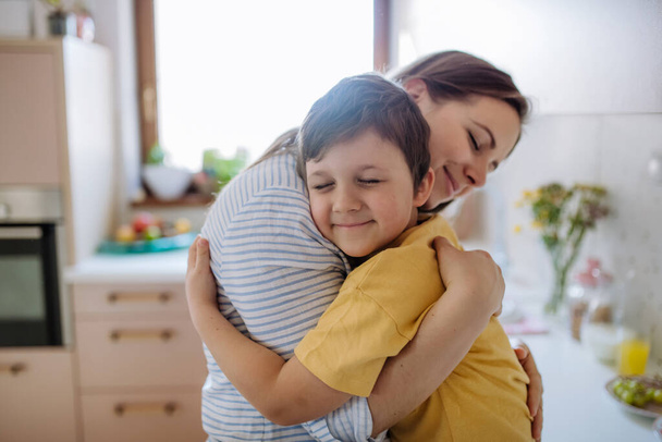 A happy oung mother hugging her little son in kitchen at home. - 写真・画像