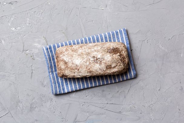 Pain de seigle frais sur serviette sur fond rustique, vue sur le dessus du pain frais. - Photo, image