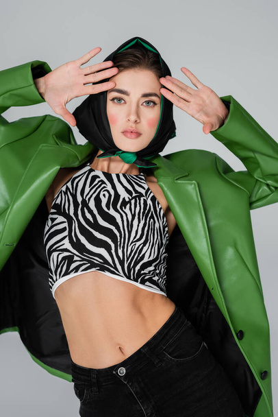 trendy woman posing in kerchief and crop top with zebra print isolated on grey - Photo, Image