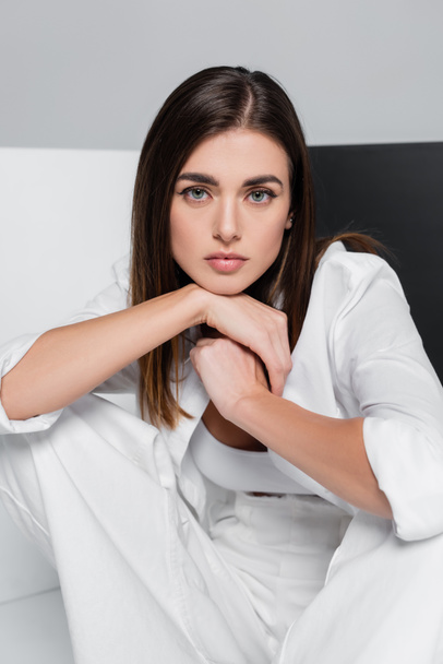 brunette woman in white clothes looking at camera on grey with black and white - Photo, Image