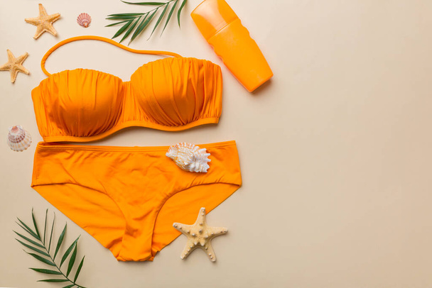 女性の水着やビーチアクセサリーフラットは、色の背景にトップビューをレイアウト夏の旅行のコンセプト。ビキニ水着、ストローハット、シーズンヒール。スペースのコピー｜Top view. - 写真・画像