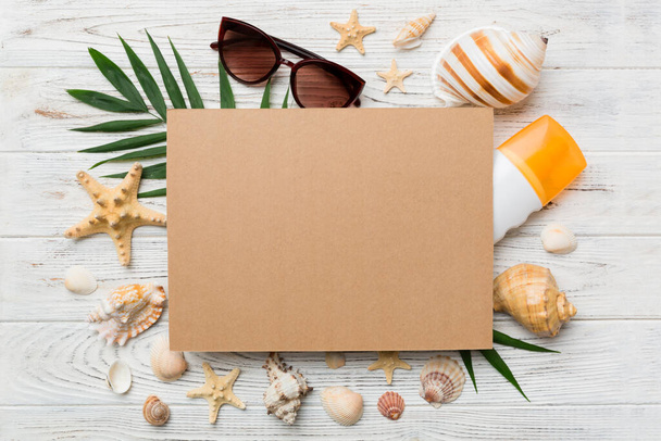 Summer time concept with blank greeting card and blank craft paper on colored background. Seashells from ocean shore in the shape of frame separated with space for text top view. - Zdjęcie, obraz