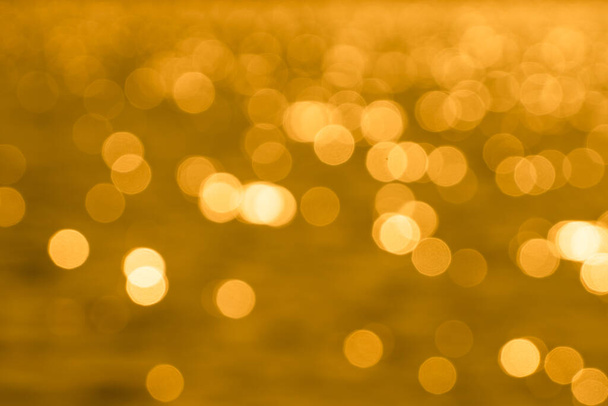 Bokeh φως από αντανάκλαση της χρυσής επιφάνειας του νερού το βράδυ ηλιοβασίλεμα - Φωτογραφία, εικόνα