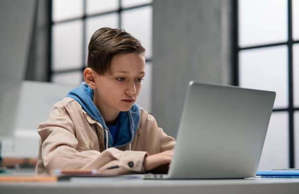 A schoolboy using computer in classroom at school - Foto, Bild