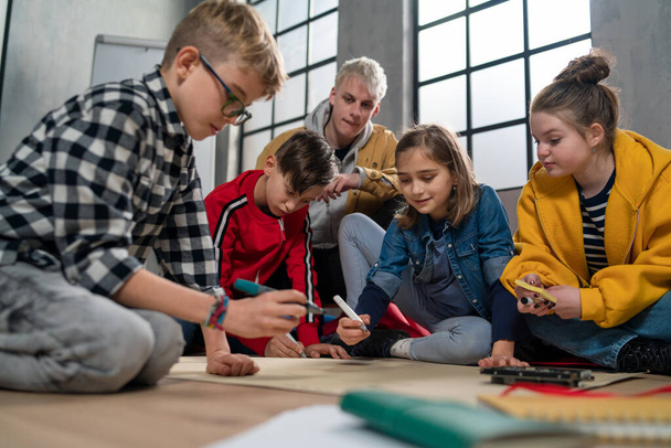 A group of happy kids with their teacher working on project together at classroom. - Fotografie, Obrázek