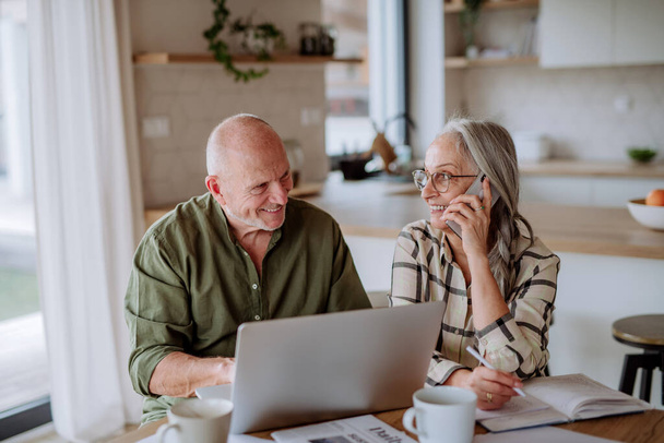 A happy senior couple calculate expenses or planning budget together at home. - Fotoğraf, Görsel