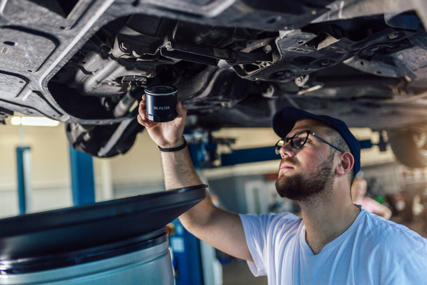 Портрет механіка, який ремонтує машину в гаражі, зміна нафти
. - Фото, зображення