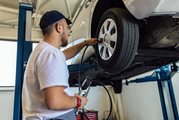 Mechanician changing car wheel in auto repair shop - Foto, Bild
