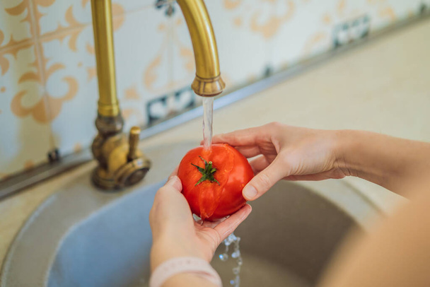 Close-up Of A Woman Washing Tomato In Running Water Under Tap. - Foto, imagen