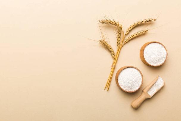 Flat lay of Wheat flour in wooden bowl with wheat spikelets on colored background. world wheat crisis. - Foto, Imagem