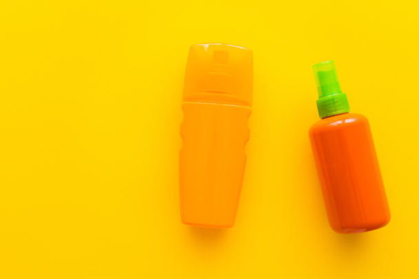 Top view of bottles of sunscreens on yellow background  - Фото, изображение