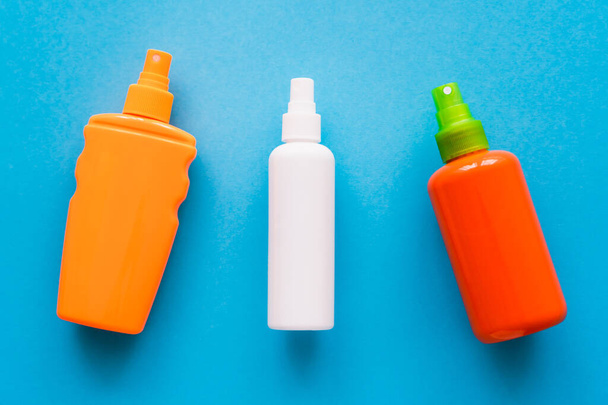 Top view of bottles of sunscreens on blue background  - Foto, immagini