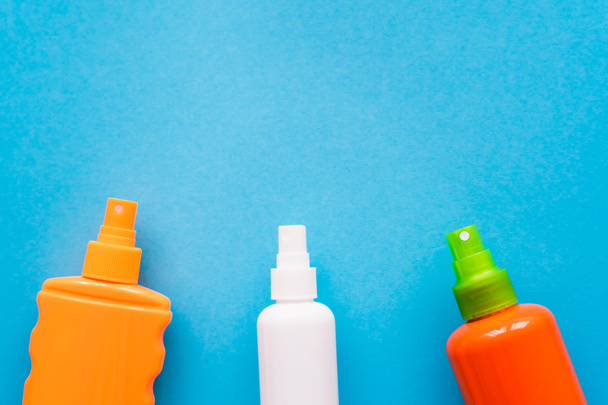 Top view of bottles of sunblock on blue background  - Photo, Image
