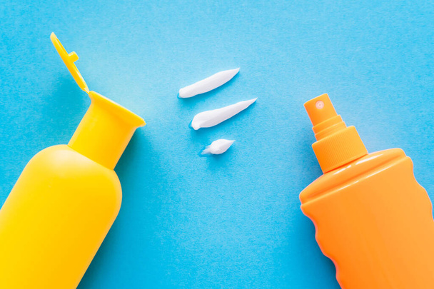 Top view of cream near sunscreens on blue background  - Fotoğraf, Görsel
