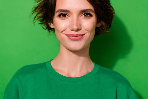 Zdjęcie uroczej młodej damy ubranej w luźny t-shirt uśmiechając się odizolowany zielony kolor tła. - Zdjęcie, obraz