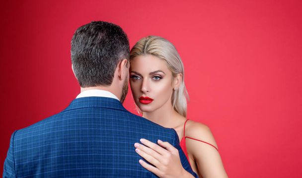 sexy couple in ove embrace on red background with copy space. - 写真・画像