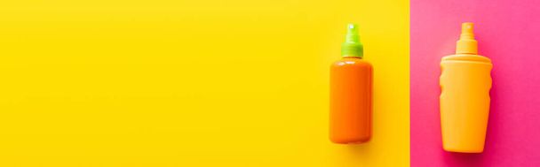 Top view of sunblock in bottles on pink and yellow background, banner  - Foto, Bild