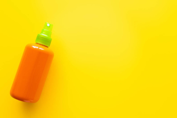 Top view of bottle of sunscreen on yellow surface  - Fotografie, Obrázek