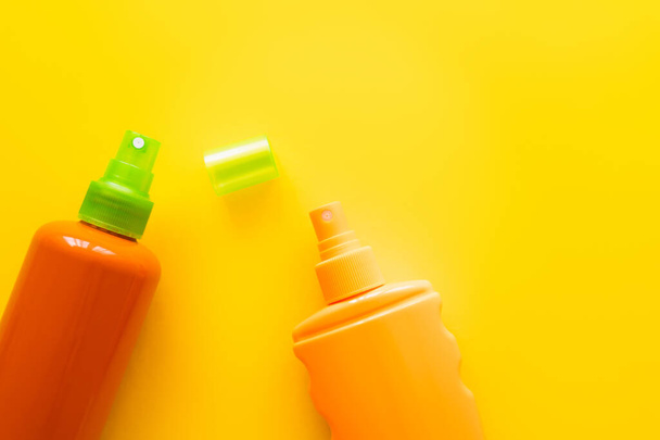 Bovenaanzicht van flessen zonnebrandcrème op geel oppervlak  - Foto, afbeelding